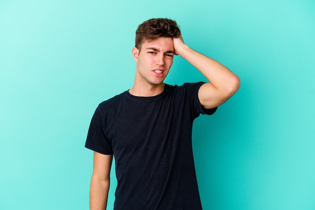 Young caucasian man isolated on blue background forgetting something, slapping forehead with palm and closing eyes.