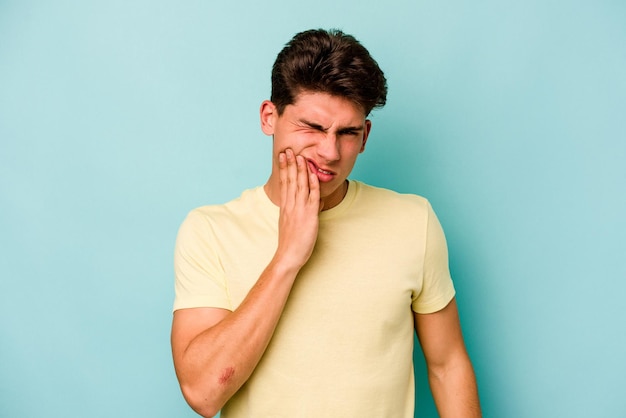 Young caucasian man isolated on blue background having a strong teeth pain molar ache