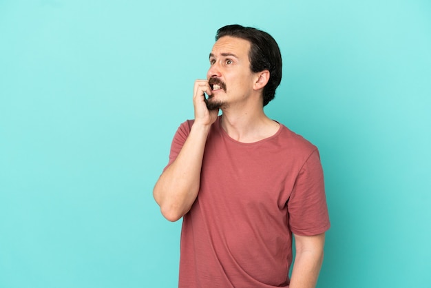 Young caucasian man isolated on blue background is a little bit nervous