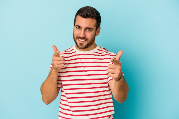 Young caucasian man isolated on blue background pointing to front with fingers.