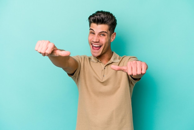 Young caucasian man isolated on blue background raising both thumbs up smiling and confident