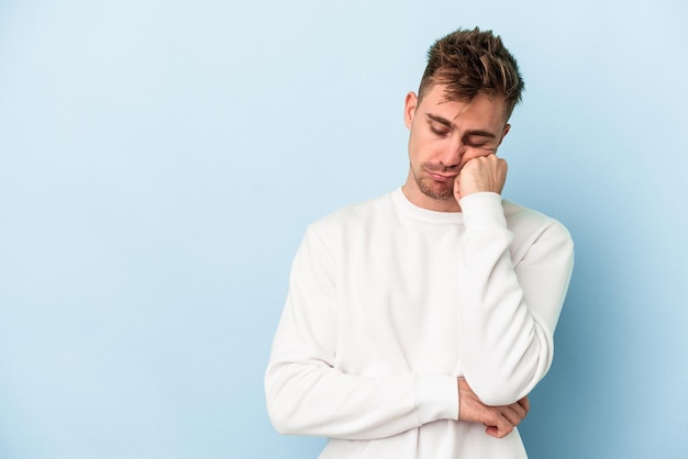 Young caucasian man isolated on blue background who feels sad and pensive, looking at copy space.