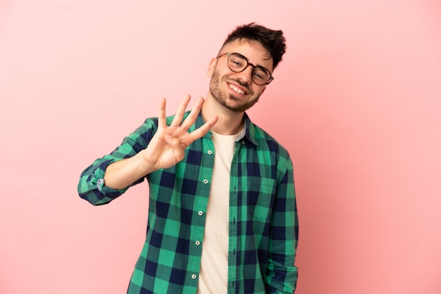 Young caucasian man isolated on pink background happy and counting four with fingers