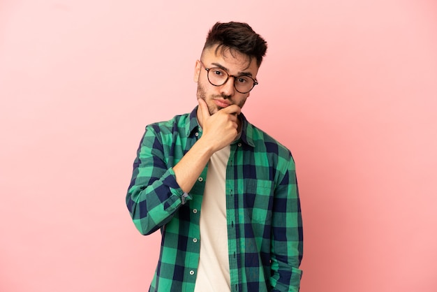 Young caucasian man isolated on pink background having doubts