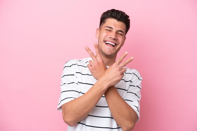 Young caucasian man isolated on pink background smiling and showing victory sign