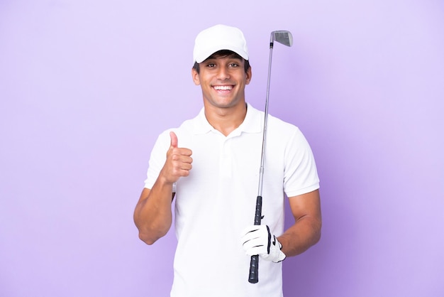 Young caucasian man isolated on purple background playing golf and with thumbs up because something good has happened