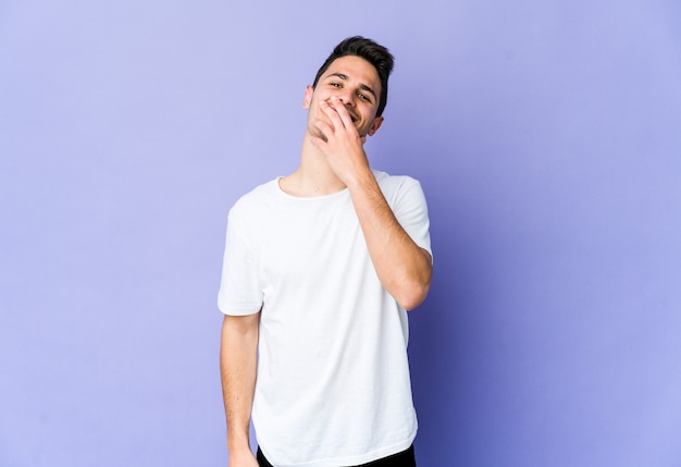 Young caucasian man isolated on purple wall laughing happy, carefree, natural emotion.