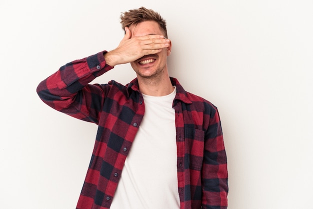 Photo young caucasian man isolated on white background covers eyes with hands, smiles broadly waiting for a surprise.