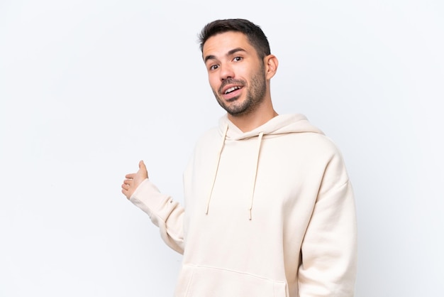 Young caucasian man isolated on white background extending hands to the side for inviting to come