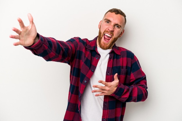 Young caucasian man isolated on white background feels confident giving a hug to the camera.