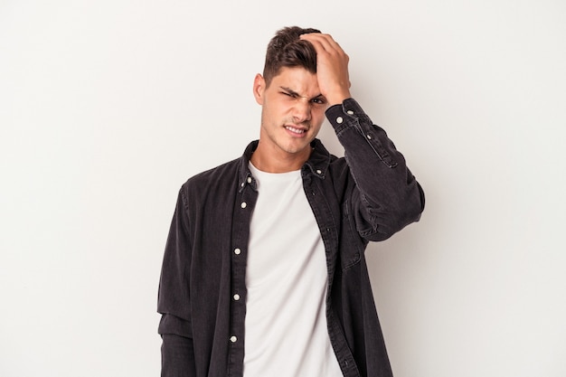 Young caucasian man isolated on white background forgetting something, slapping forehead with palm and closing eyes.