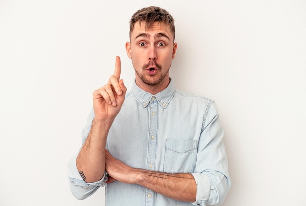 Young caucasian man isolated on white background funny and friendly sticking out tongue.