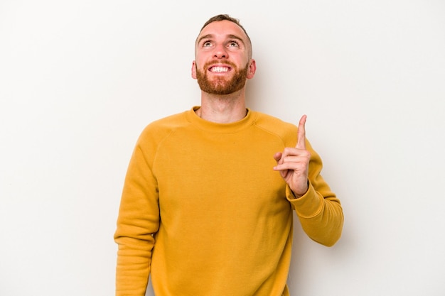 Photo young caucasian man isolated on white background indicates with both fore fingers up showing a blank space