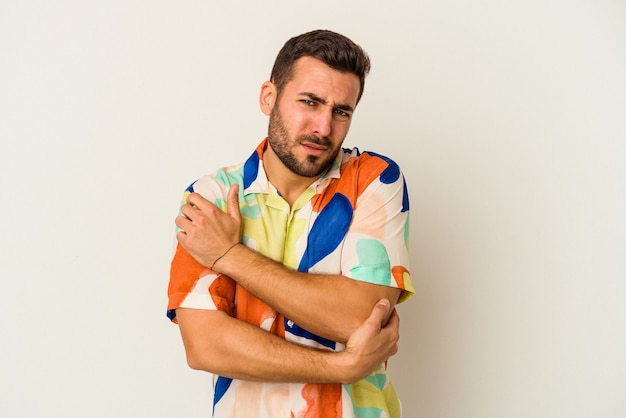 Young caucasian man isolated on white background massaging elbow, suffering after a bad movement.