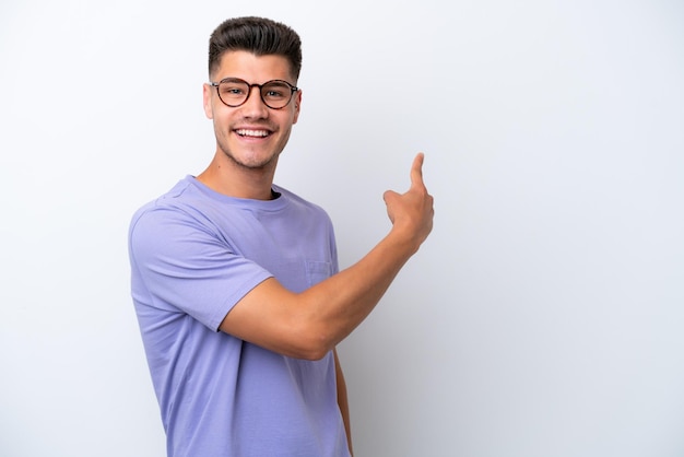 Young caucasian man isolated on white background pointing back