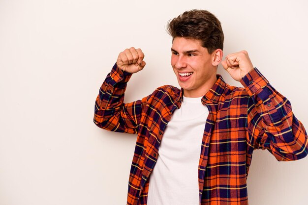 Young caucasian man isolated on white background raising fist after a victory winner concept