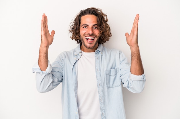 Young caucasian man isolated on white background receiving a pleasant surprise, excited and raising hands.