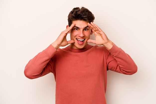 Young caucasian man isolated on white background receiving a pleasant surprise excited and raising hands