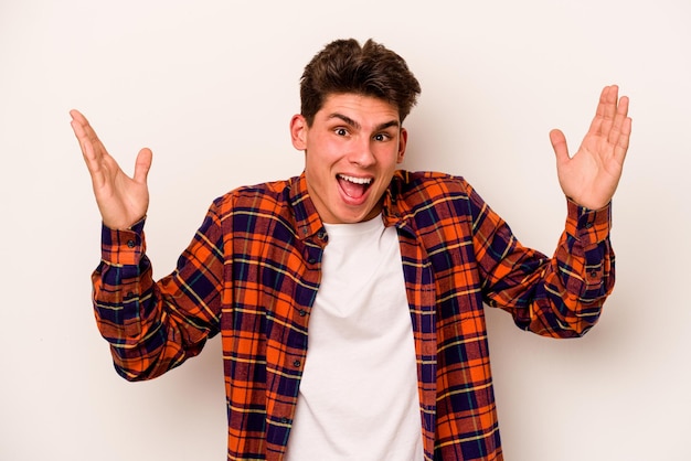 Young caucasian man isolated on white background receiving a pleasant surprise excited and raising hands