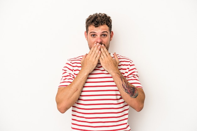 Young caucasian man isolated on white background shocked, covering mouth with hands, anxious to discover something new.