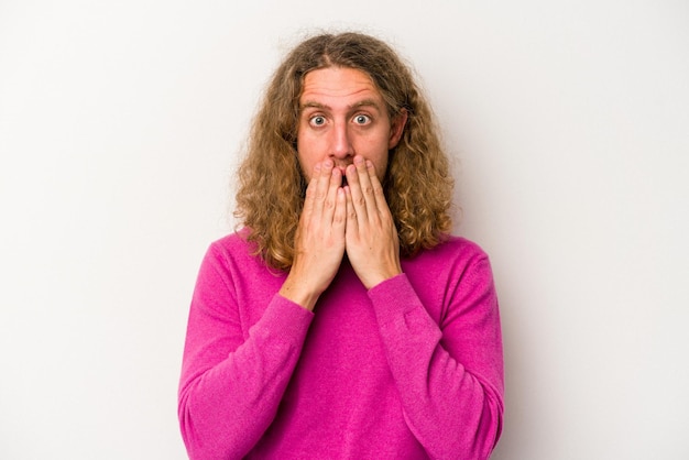 Young caucasian man isolated on white background shocked covering mouth with hands anxious to discover something new