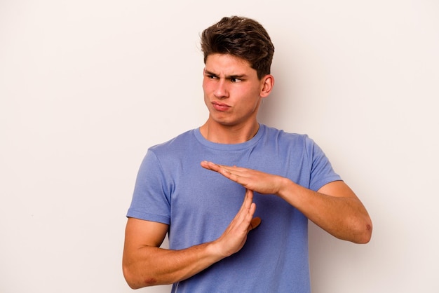 Young caucasian man isolated on white background showing a timeout gesture