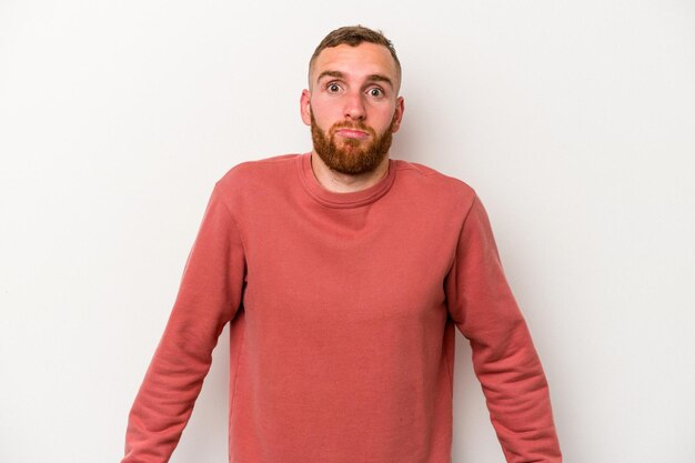 Photo young caucasian man isolated on white background shrugs shoulders and open eyes confused