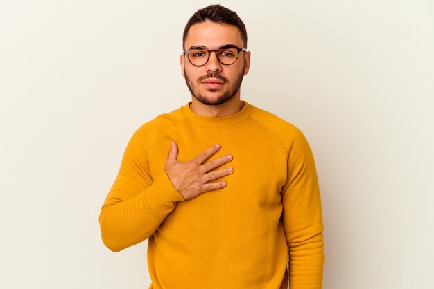 Young caucasian man isolated on white background taking an oath, putting hand on chest.