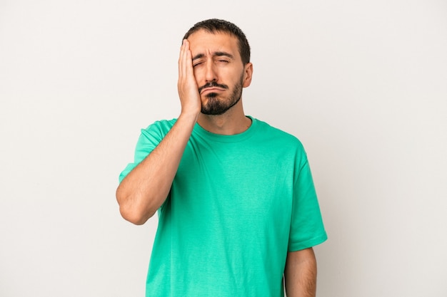 Young caucasian man isolated on white background tired and very sleepy keeping hand on head.