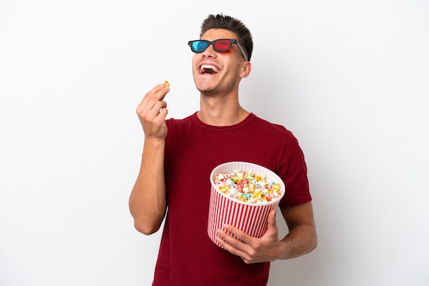 Young caucasian man isolated on white background with 3d glasses and holding a big bucket of popcorns