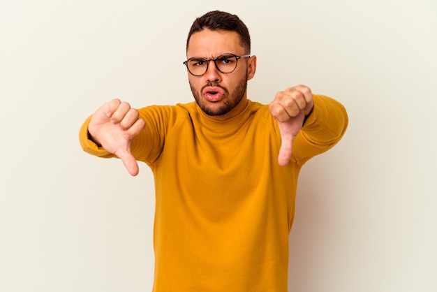 Young caucasian man isolated on white showing thumb down and expressing dislike.