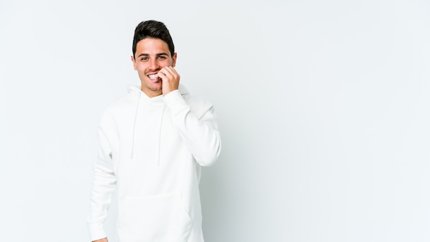 Young caucasian man isolated on white wall biting fingernails, nervous and very anxious.