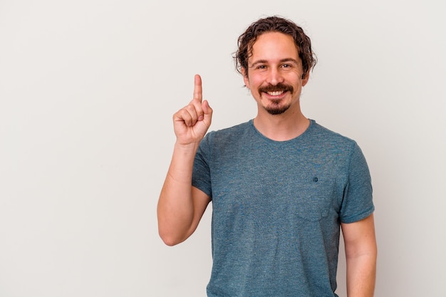 Young caucasian man isolated on white wall showing number one with finger.