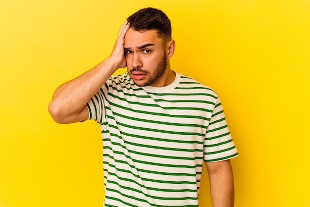 Young caucasian man isolated on yellow background being shocked, she has remembered important meeting.