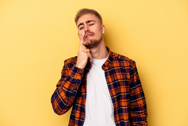 Young caucasian man isolated on yellow background crying, unhappy with something, agony and confusion concept.