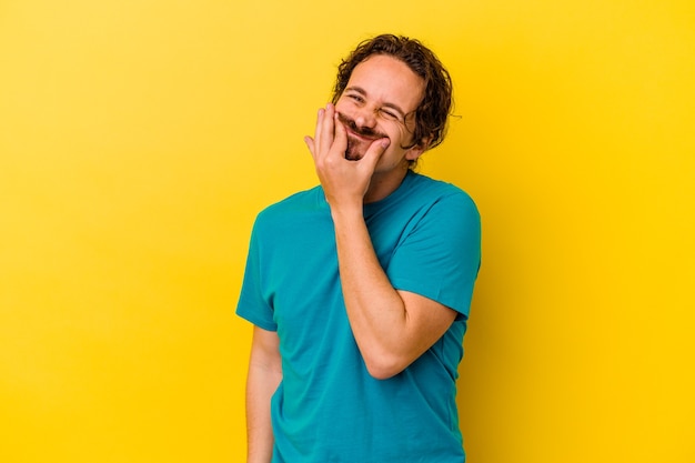 Young caucasian man isolated on yellow background doubting between two options.