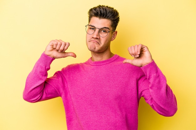 Photo young caucasian man isolated on yellow background feels proud and self confident example to follow