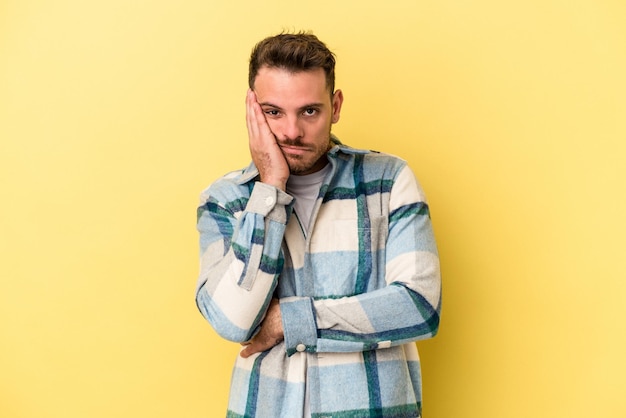 Young caucasian man isolated on yellow background who is bored fatigued and need a relax day