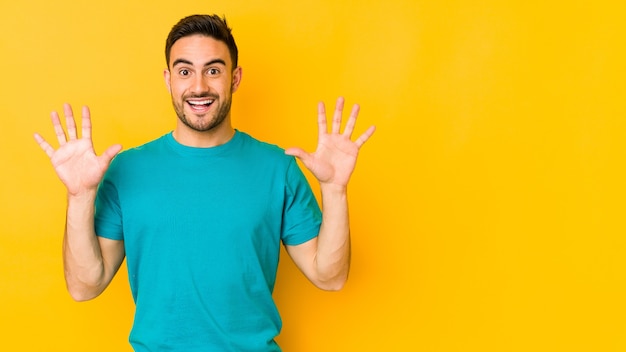 Young caucasian man isolated on yellow receiving a pleasant surprise, excited and raising hands.