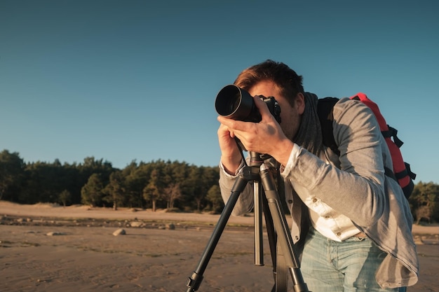 Young caucasian man making photo of landscape on seaside