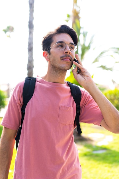 Young caucasian man at outdoors in a park using mobile phone