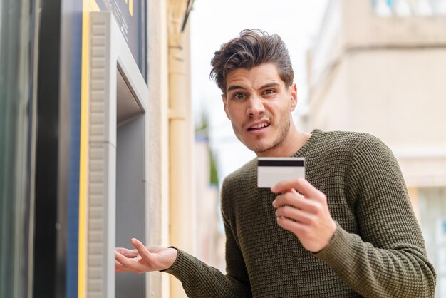 Young caucasian man at outdoors using an ATM