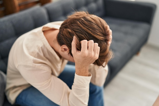 Young caucasian man patient stressed sitting on sofa at home