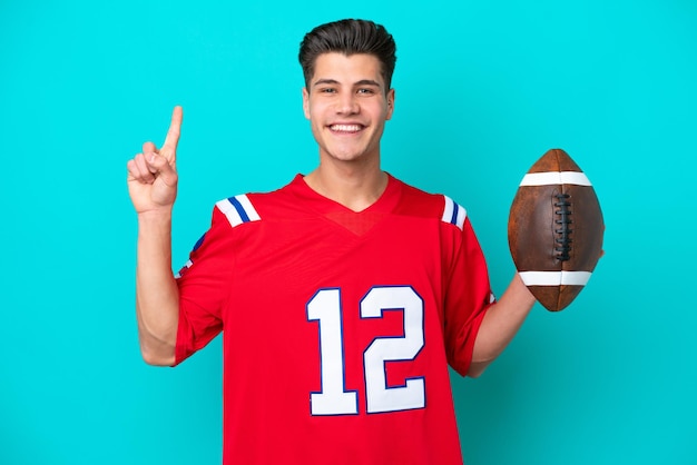 Young Caucasian man Playing rugby isolated on blue background showing and lifting a finger in sign of the best