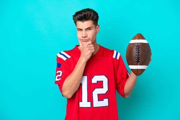 Young Caucasian man Playing rugby isolated on blue background thinking