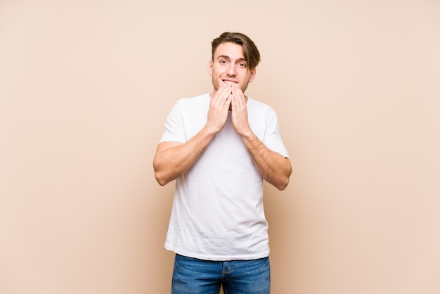 Young caucasian man posing isolated laughing about something, covering mouth with hands.