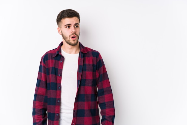 Young caucasian man posing in a white isolated being shocked because of something she has seen.