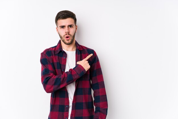 Young caucasian man posing on white isolated pointing to the side