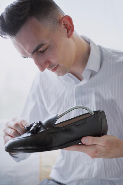 Young caucasian man repairing old male leather shoes.