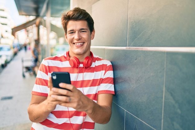 Young caucasian man smiling happy using smartphone and headphones at the city.